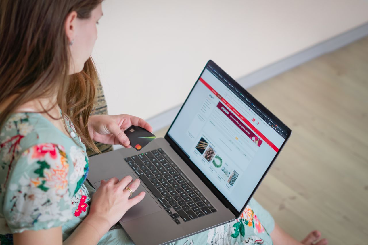 services-08 Žena u cvjetnoj haljini kupuje online s laptopom i kreditnom karticom u zatvorenom prostoru.
